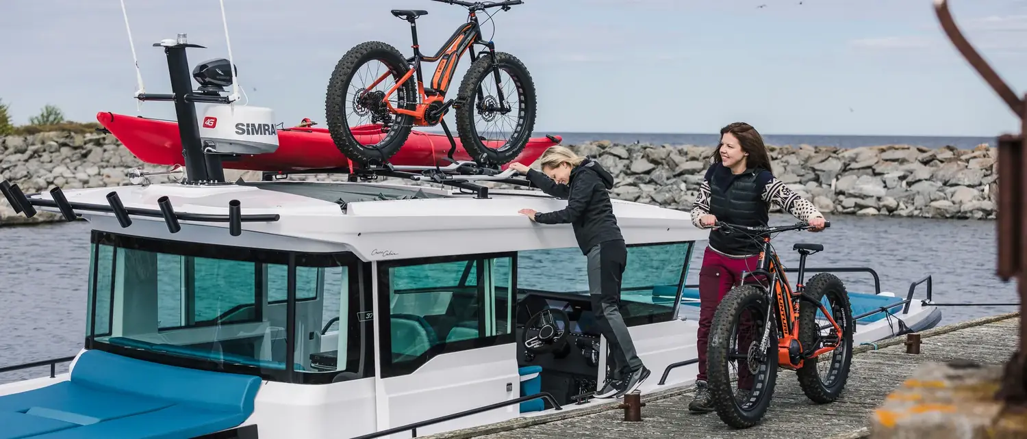 Dos personas cargan bicicletas en la cubierta de una embarcación amarrada al muelle